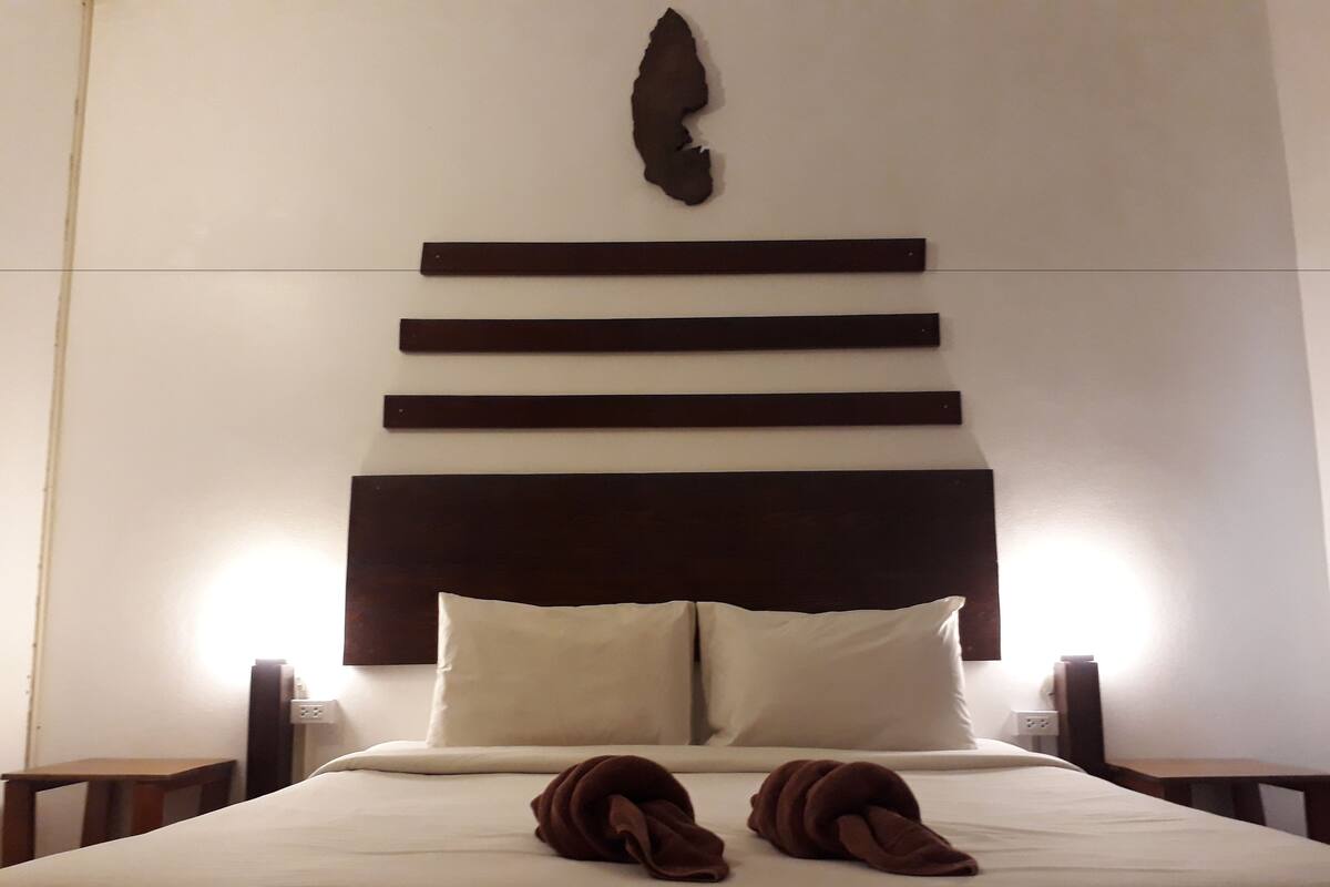 A neatly made bed with a headboard featuring horizontal wooden panels and a decorative element above it.