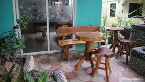 A patio area with a wooden bench, a round table, and two stools. - Blue Lotus Hotel (Boracay Island)