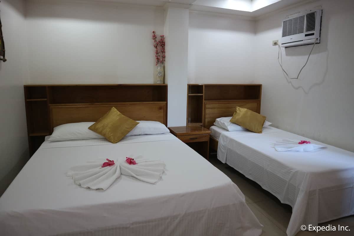 A hotel room with two single beds, a wooden headboard, a nightstand, and an air conditioning unit on the wall.