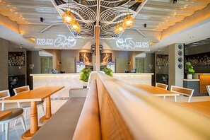 A modern cafe interior with a central counter, seating area, and decorative lighting. - OYO 595 Klm Condotel (Angeles City)