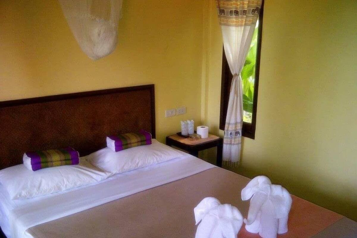 Habitación de hotel con cama, mesita de noche y ventana con cortinas.