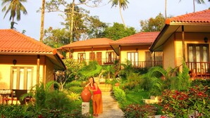 A resort with multiple bungalow-style buildings, each with a red-tiled roof and a small balcony. The buildings are surrounded by lush greenery and palm trees. - Paradise Bungalows (Ko Chang)