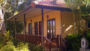 A yellow building with a tiled roof, wooden balcony, and a small garden area. - Paradise Bungalows (Ko Chang)