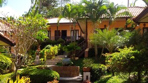 A pathway leading to a building with a tiled roof, surrounded by lush greenery and palm trees. - Paradise Bungalows (Ko Chang)