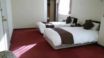Une chambre d’hôtel avec deux lits, une moquette rouge et une porte.
