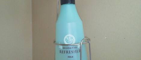 A blue bottle labeled "aroma ess REFRESHER POLA" mounted on a metal hook.