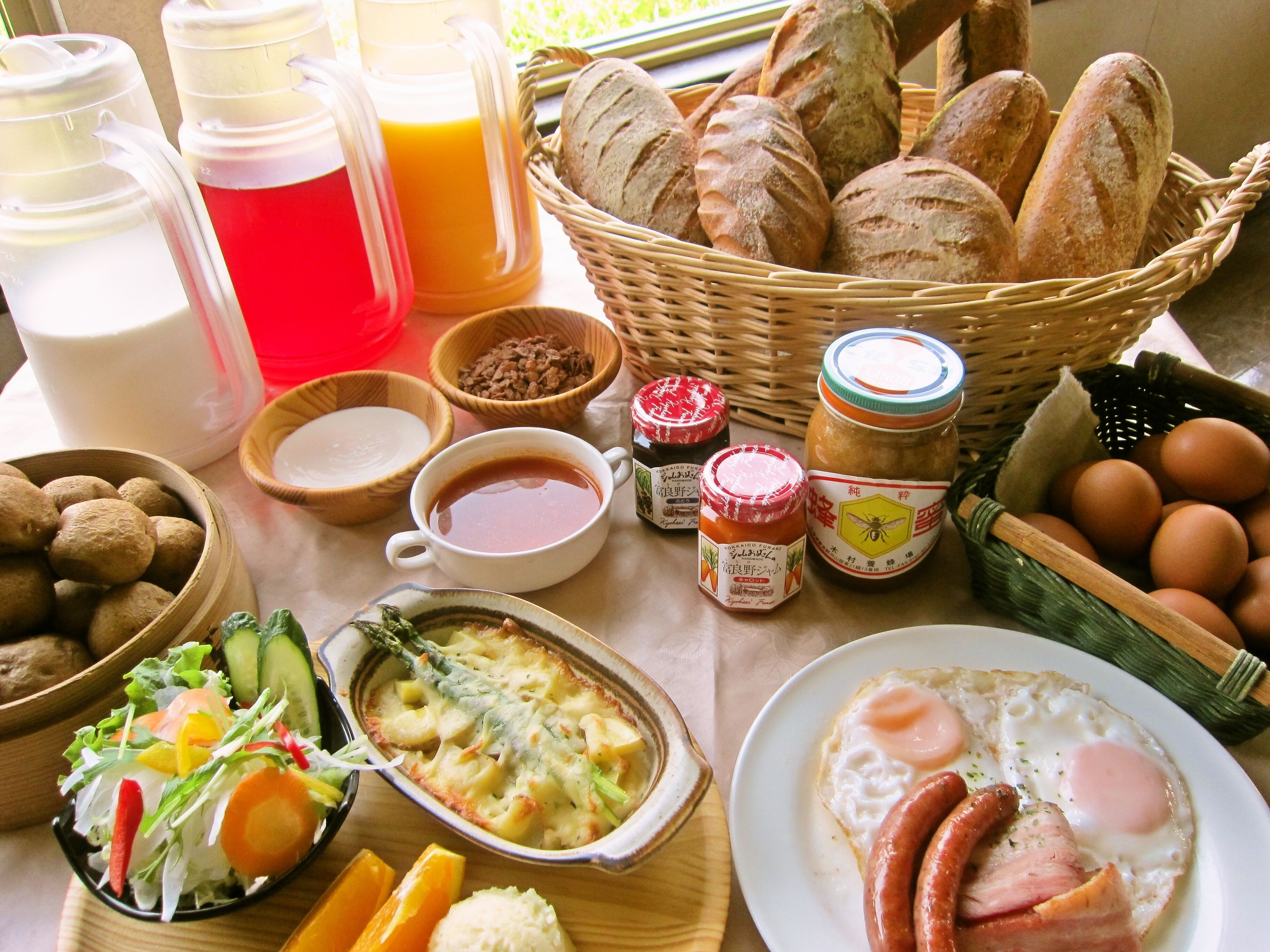 A breakfast spread with bread, eggs, sausages, and various condiments.