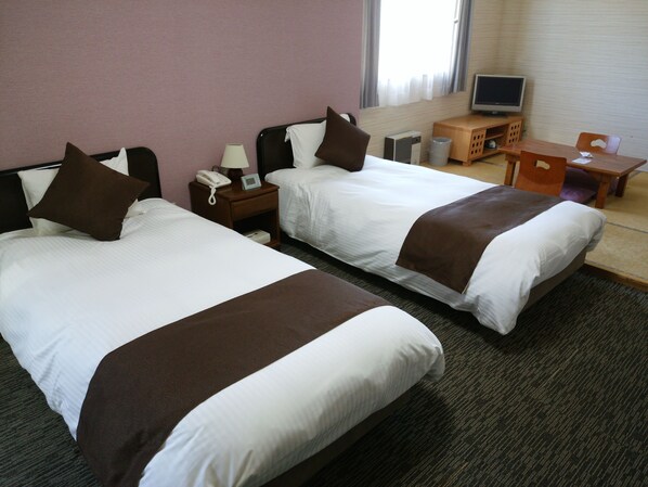 A hotel room with two beds, a desk, a chair, a TV, and a telephone. - Resort Inn North Country (Furano)
