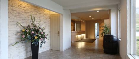A spacious hallway with a stone wall, a potted plant, and a large barrel.