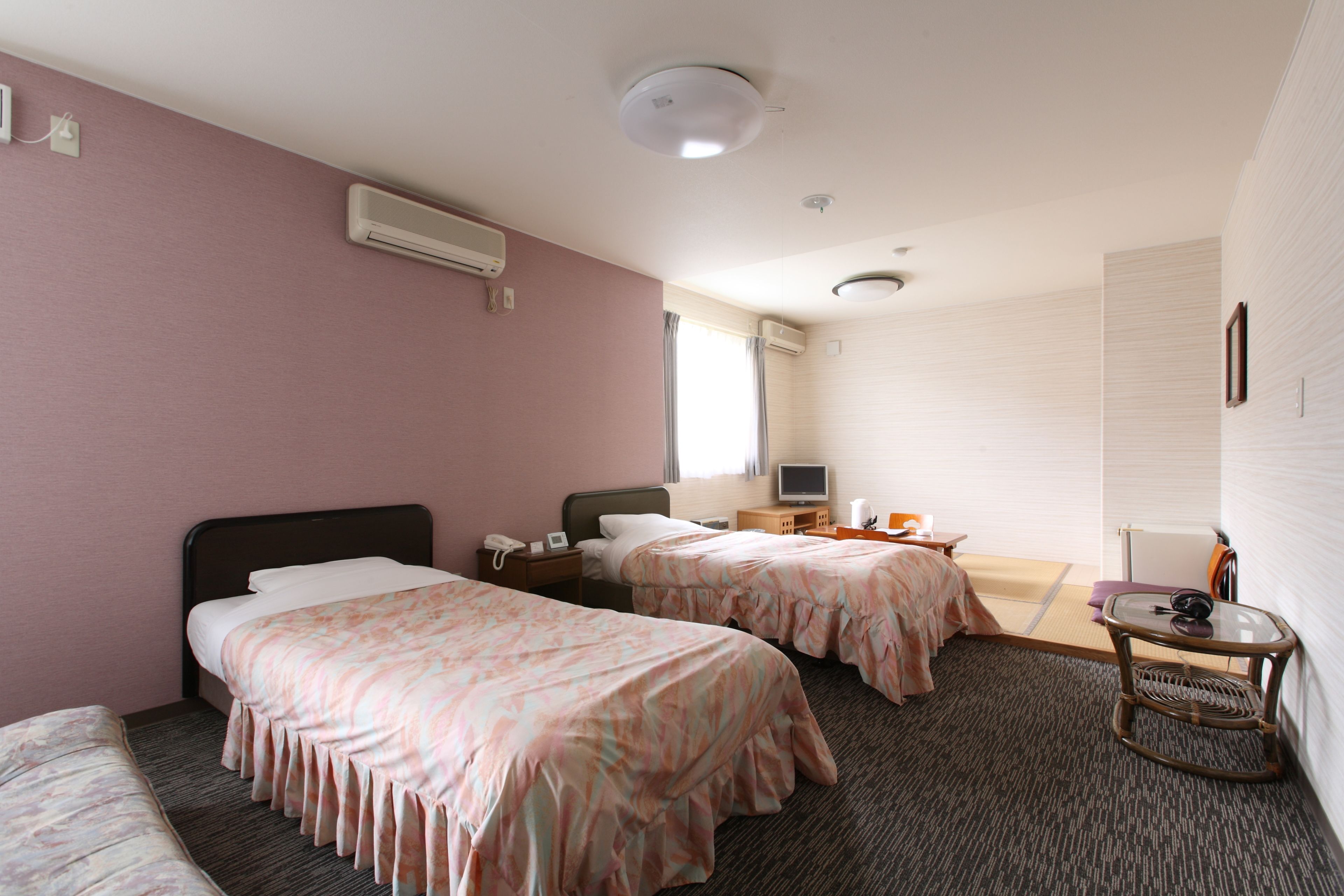 A hotel room with two beds, a television, a small table, and a chair.