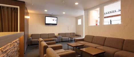 A modern living room with a sectional sofa, armchairs, and a TV mounted on the wall.