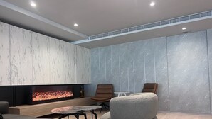 Una sala de estar moderna con chimenea, asientos cómodos y una pared de mármol.