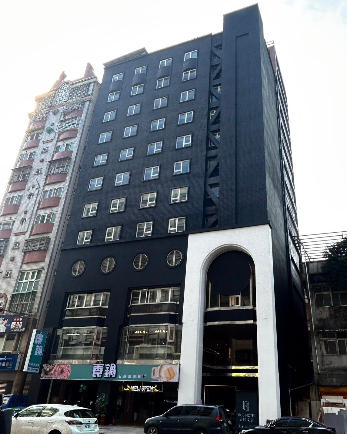 Un hôtel à plusieurs étages doté d’une façade moderne, caractérisé par une entrée arquée imposante et de nombreuses fenêtres.