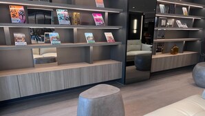 Una biblioteca moderna con estanterías, zonas de estar y un muro reflectante.