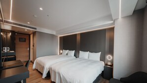 Una habitación de hotel moderna con dos camas, un escritorio y una zona de estar.