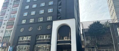 A modern hotel with a prominent entrance, multiple floors, and a mix of commercial spaces on the ground level.