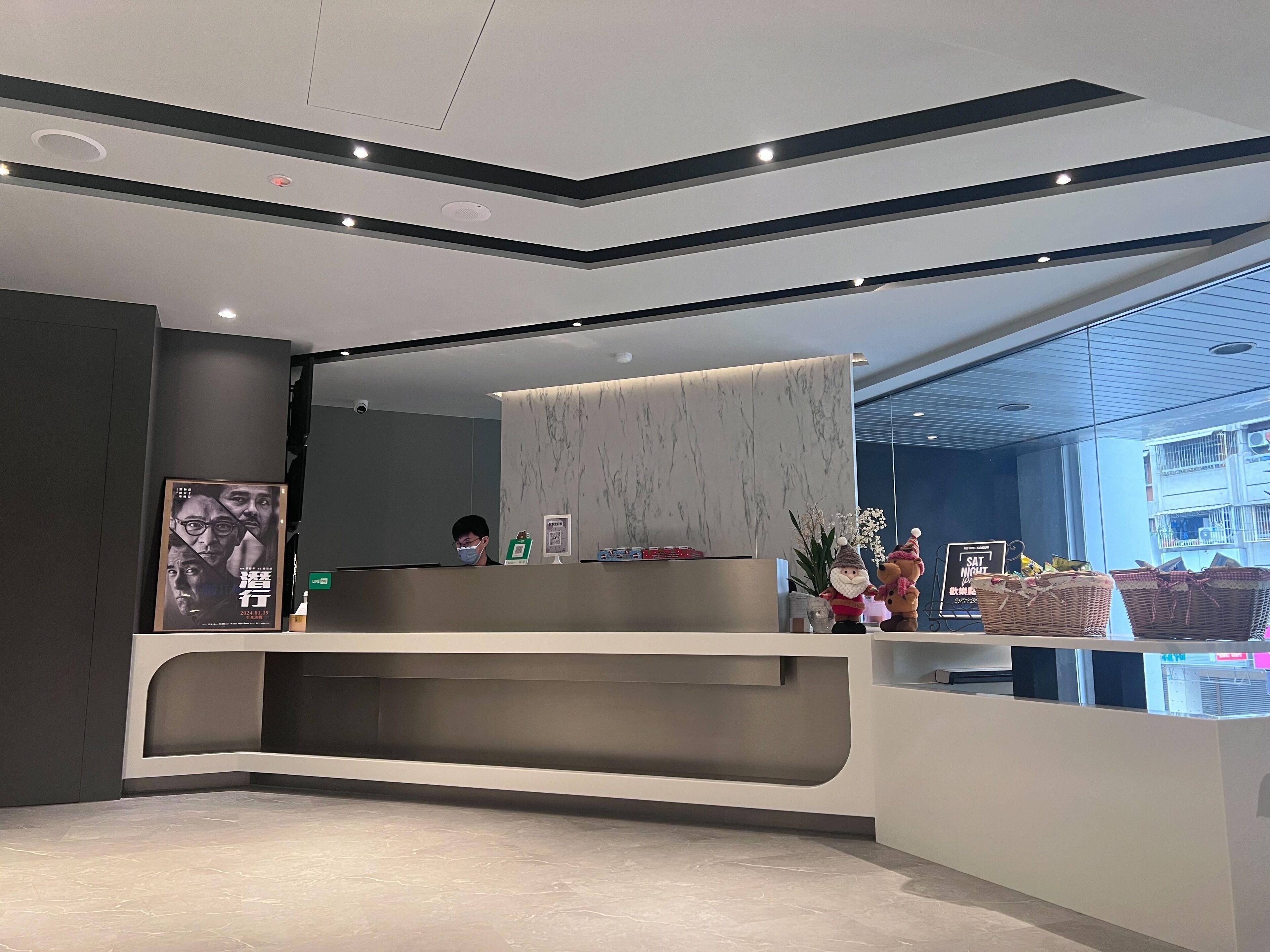A modern reception desk with a marble-like wall, a security camera, and a poster on the wall.