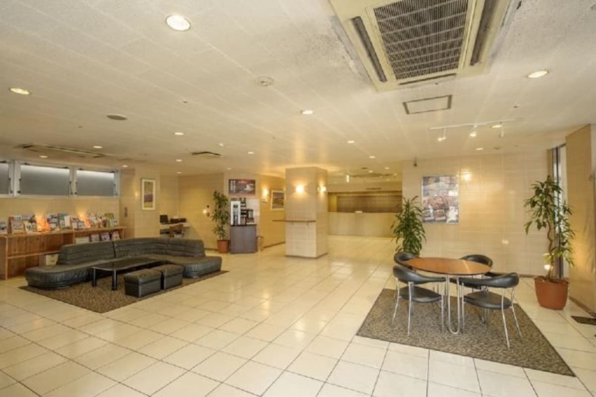 A spacious lobby with a sectional sofa, a dining area, and a reception desk.