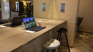 A modern reception desk with laptops, a coffee cup, and a plant. - Court Hotel Mito (Mito)