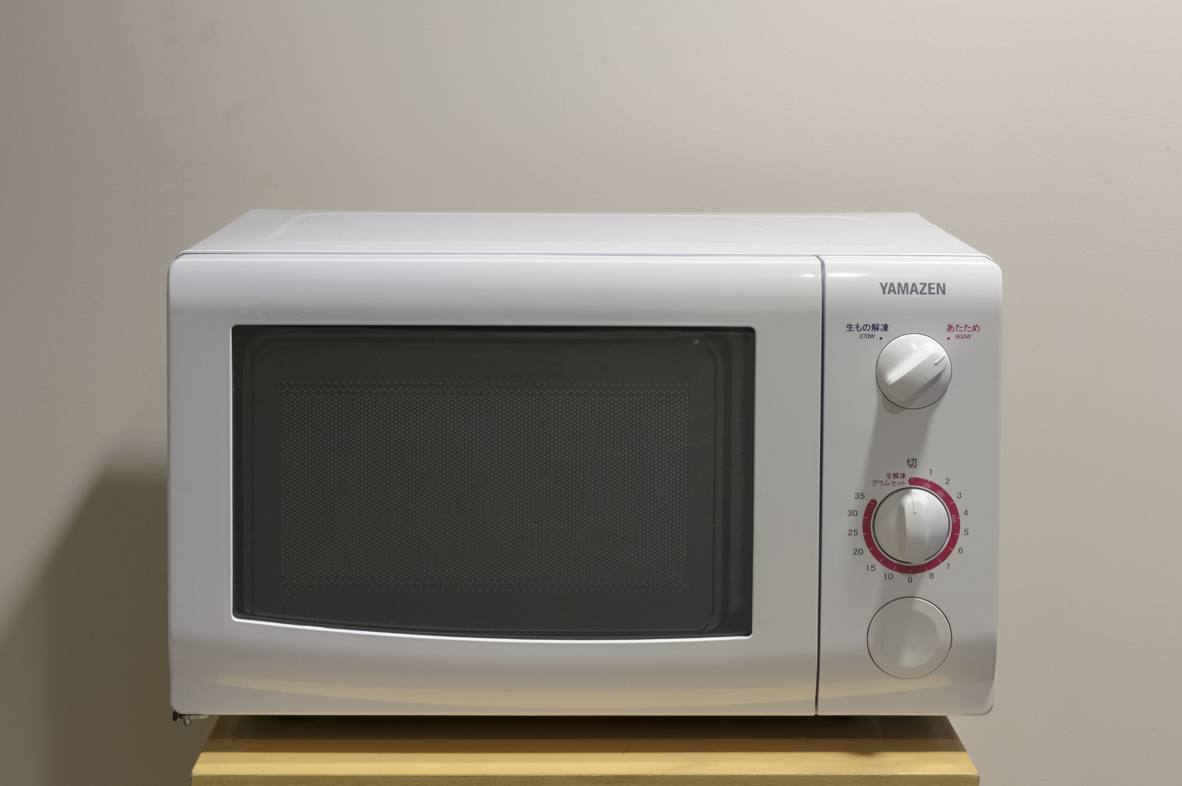 A white microwave oven with a control panel, placed on a wooden surface.