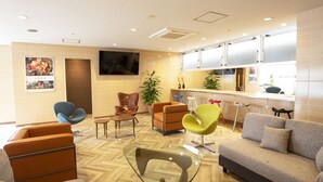 A modern hotel lobby with a mix of seating options, including a sofa, armchairs, and a glass-top table. - Court Hotel Mito (Mito)