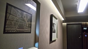 A hallway with a patterned wall, a framed picture, and a door marked with the number 707. - Paris Business Hotel (Kaohsiung)