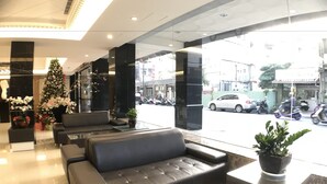 A modern lobby with a black leather sofa, a glass reception desk, and a Christmas tree. - Paris Business Hotel (Kaohsiung)