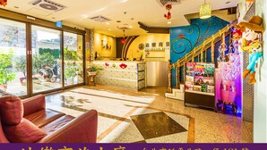 A hotel lobby with a reception desk, a staircase with decorative elements, and a seating area with a sofa. - The Dealer Hotel (Taipei)