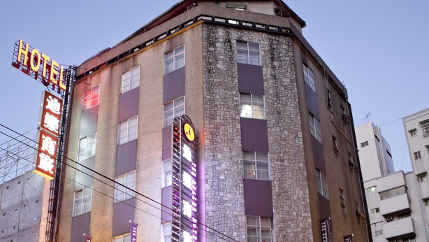 A hotel with a prominent sign, multiple floors, and a parking lot. - The Dealer Hotel (Taipei)