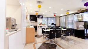 A modern hotel dining area with a coffee machine, a TV, and a seating area with tables and chairs. - The Dealer Hotel (Taipei)