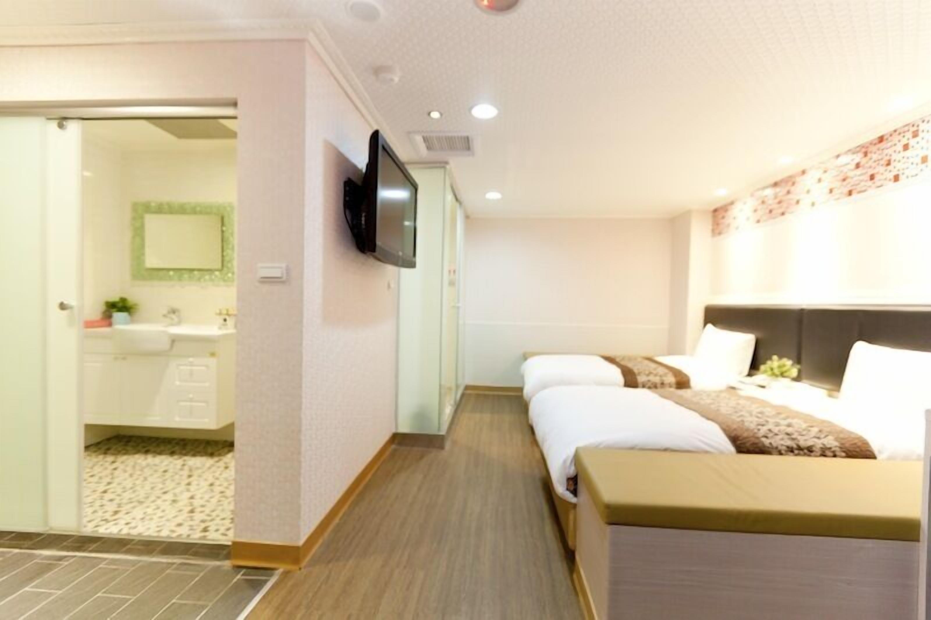 A hotel room with a bed, a television mounted on the wall, and a bathroom visible through an open door.