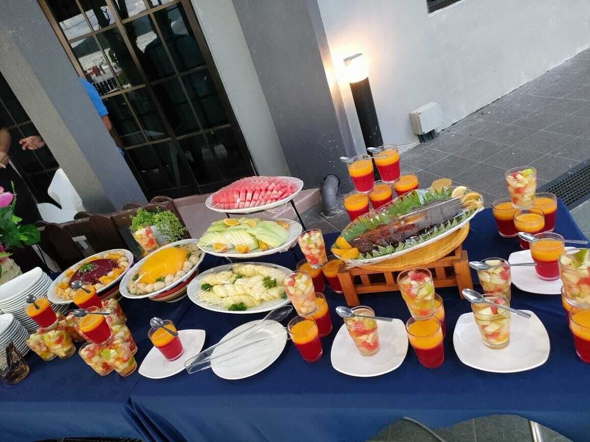 A buffet table with various dishes and drinks, including fruits, salads, and a variety of beverages.
