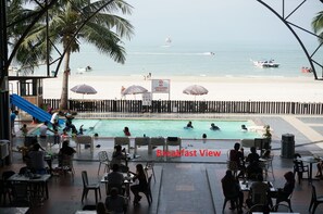 A poolside area with a view of the beach, a lifeguard sign, and a slide. - Best Star Resort (Langkawi)