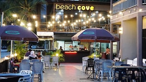 An outdoor seating area with umbrellas, tables, and chairs at a beach-themed restaurant.