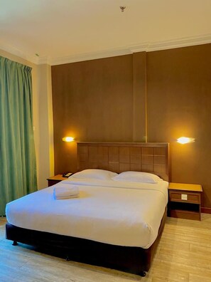 A hotel room with a large bed, two bedside tables, a wooden headboard, and two wall-mounted lights. - Best Star Resort (Langkawi)