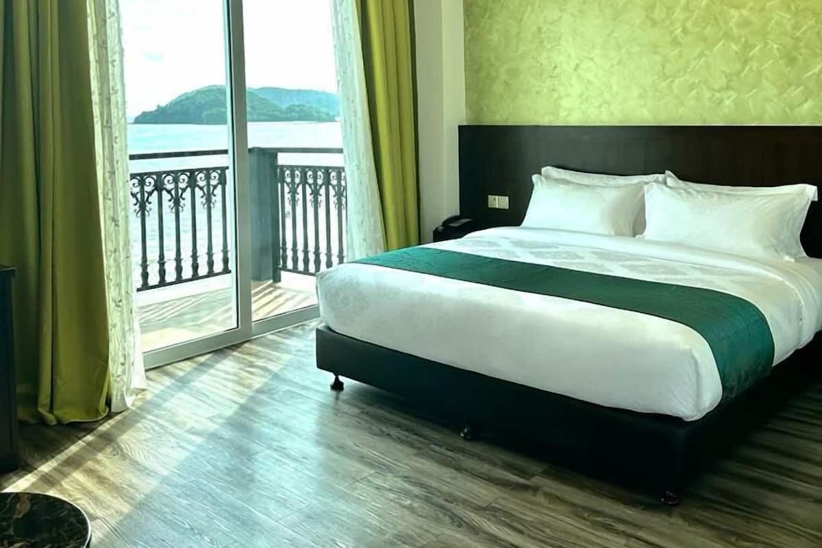 A hotel room with a bed, a nightstand, a chair, and a view of the sea through a balcony.