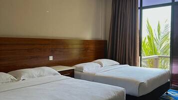 Habitación de hotel con dos camas, cabecero de madera, mesita de noche y un ventanal con cortinas.