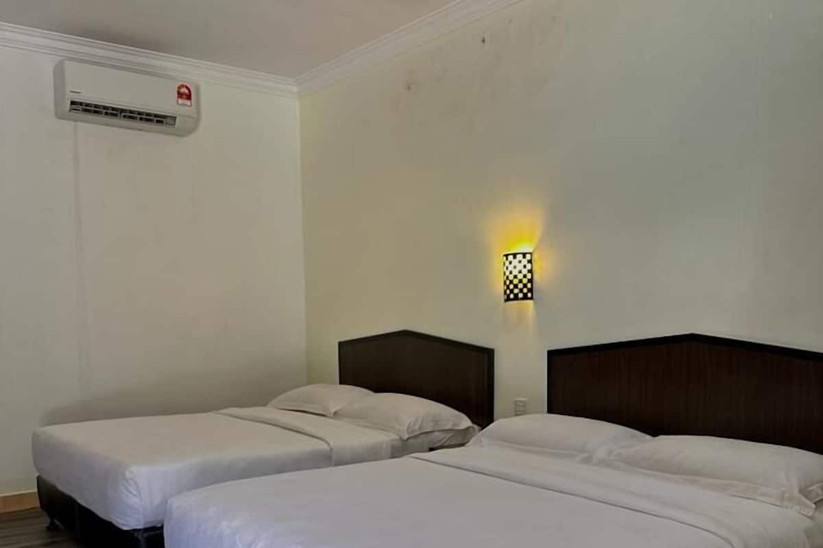 A hotel room with two beds, a wall-mounted air conditioner, and a wall-mounted light fixture.