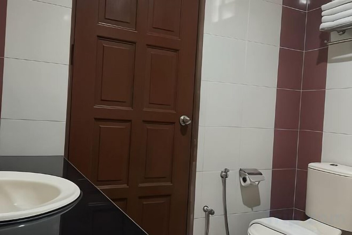 Un baño con inodoro, lavamanos, toallero y puerta.
