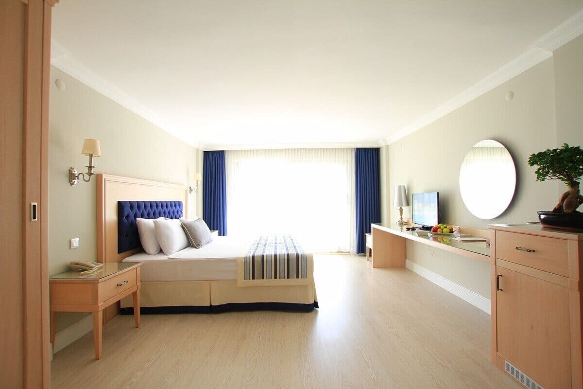 Un dormitorio con cama, mesita de noche, lámpara, cómoda y un espejo grande.