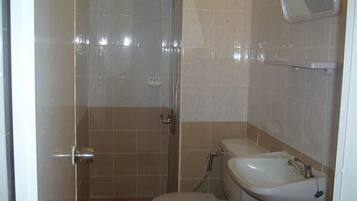 A bathroom with a shower, toilet, sink, and a mirror on the wall.