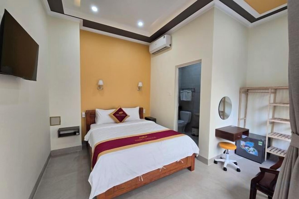 Una habitación de hotel con cama, escritorio, silla y televisor.