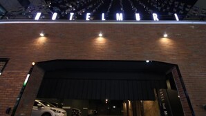 A hotel entrance with a brick facade and illuminated signage spelling "HOTEL MURRI".