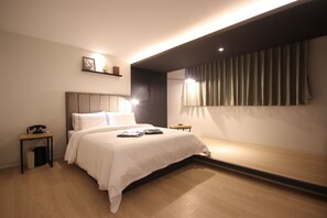 A modern hotel room with a large bed, bedside table, and a small table with a lamp. - Muri Hotel (Busan)