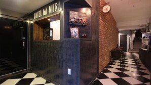 A hotel lobby with a checkered floor, a reception desk, and a wall-mounted clock.
