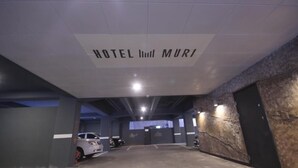 A parking garage with a sign reading "HOTEL MURI" on the ceiling.