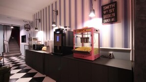 A hotel reception area with a check-in counter, a vending machine, and a sign indicating the location as Smith 9th St, Brooklyn Church Ave.