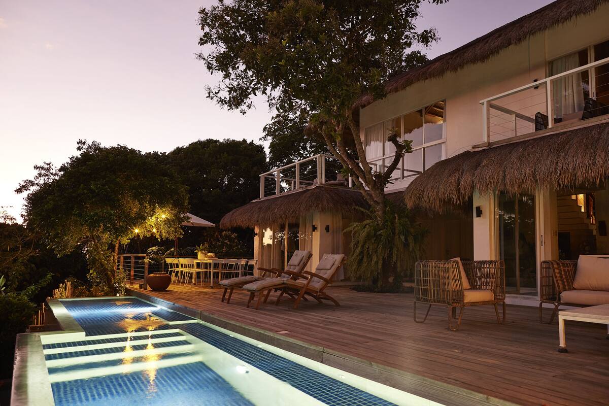 Un área de piscina con sillas de descanso y una terraza de madera.