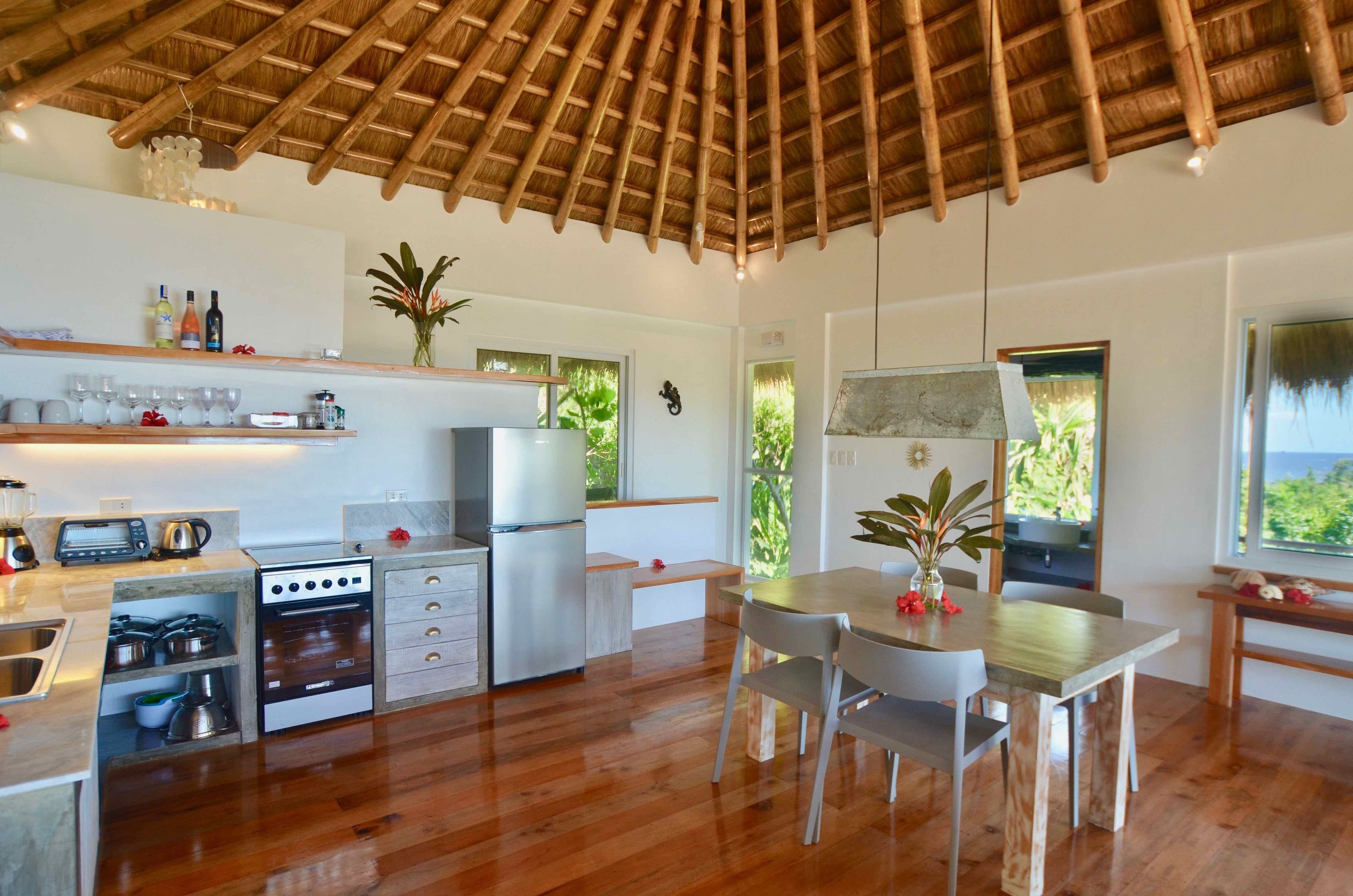 A modern kitchen with a wooden ceiling, built-in appliances, and a dining area with a table and chairs.