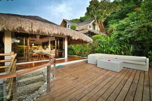 A wooden deck with a thatched-roof structure, white outdoor furniture, and lush greenery. - Diniview Villa Resort (Boracay Island)